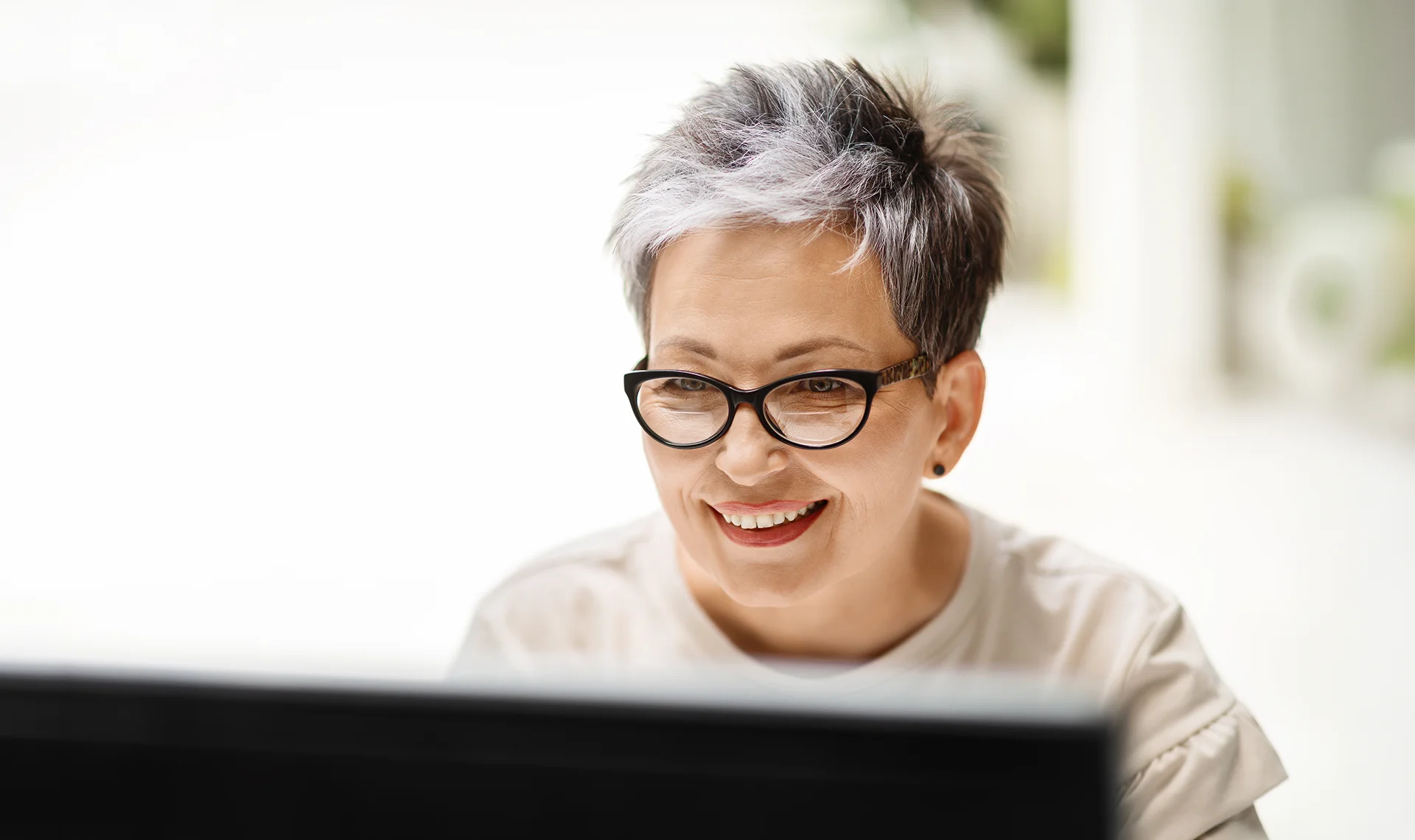 smiling woman starting the retirement enrollment process on her computer