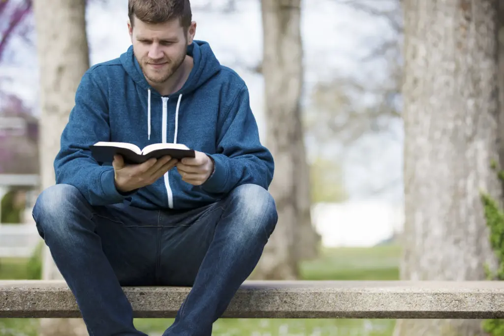 young guy in hoodie reading BIble